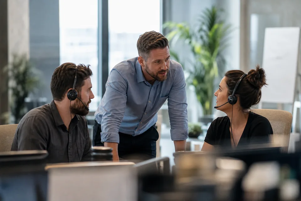 Sales manager talking with two reps in headsets about their calling setup