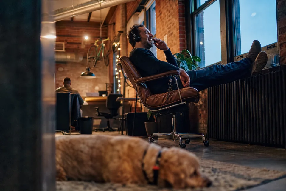 Sales rep on a headset laughing during a call in a brick warehouse office at dusk